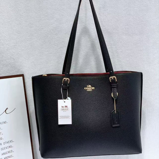 Black handbag with a visible brand tag on a light gray background